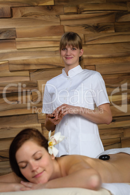 Professional masseur woman give lava stone massage