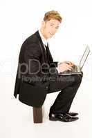 businessman with laptop sitting on a suitcase