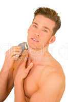 Young man shaves with electric razor