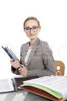 Junge Frau mit Ordnern im Büro an einem Schreibtisch