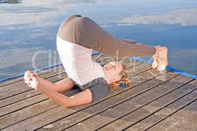 Frau beim Yoga am See