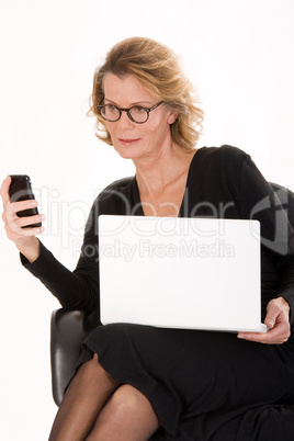 ältere Sekretärin mit Laptop beim SMS versand