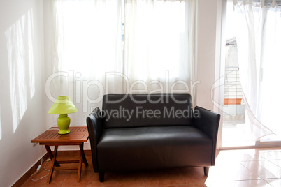 black sofa and a lamp on the bedside table on a background of cu