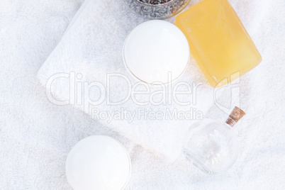 cosmetic containers, bottles, soap and lavender on a white towel