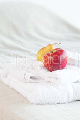 apple and pear on towels on the bed