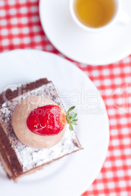 beautiful cake with strawberry and tea on plaid fabric