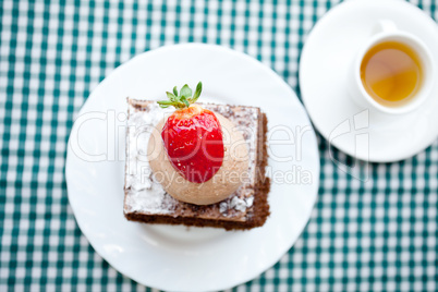 beautiful cake with strawberry and tea on plaid fabric