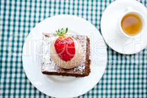 beautiful cake with strawberry and tea on plaid fabric