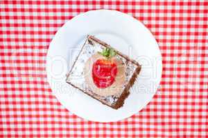 beautiful cake with strawberry on plaid fabric