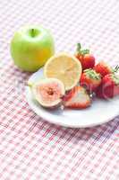 apple,lemon, fig and strawberries on a plate