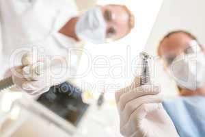 Female dentist and assistant focus on drill