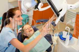 Dentist showing child dental procedure on monitor