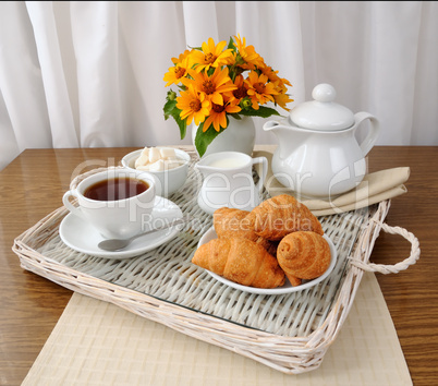 croissants with tea and milk on a tray