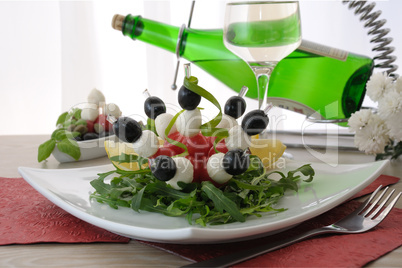 Appetizer of mozzarella, cherry tomatoes and olives with Arugula