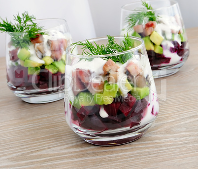 Appetizer in a glass of beet and herring with avocado