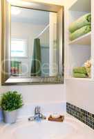 New beautiful white sink with green towels and mirror.