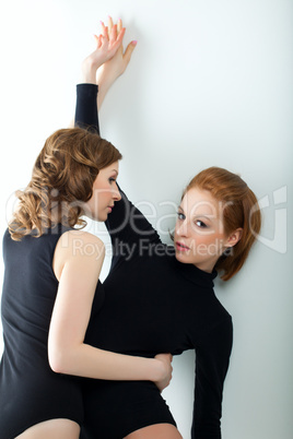 Two beauty woman in tank top near wall