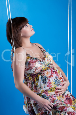 Pregnant woman sitting on swing in studio
