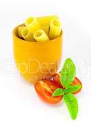 Rigatoni pasta in an orange jar with tomatoes and basil