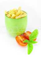 Fusilli pasta in a green jar with tomatoes and basil