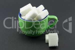 A small green cup full of sugar cubes