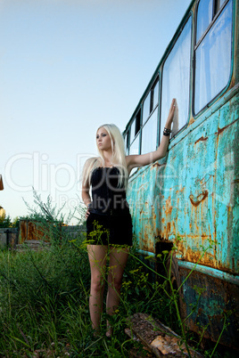 Blonde woman standing near abandoned bus