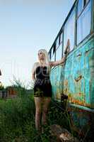 Blonde woman standing near abandoned bus