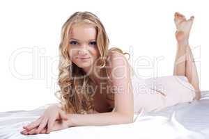 Pretty young woman lying on white sheet