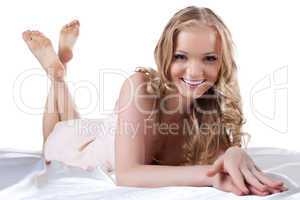 Smiling young woman lying on white sheet