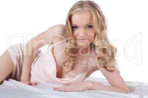 Blonde young woman lying on white sheet