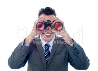 Smiling businessman looks through binoculars