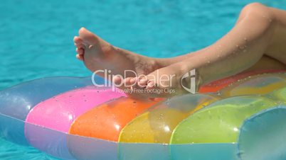 Female Legs on Pool Raft In Swimming Pool