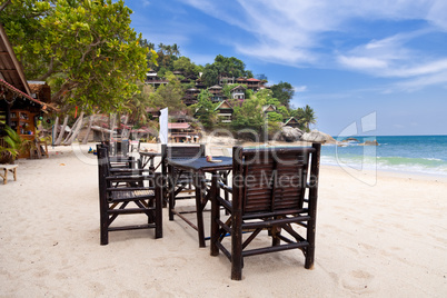 Chairs and table on the sand beach with blue sky