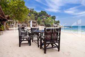Chairs and table on the sand beach with blue sky
