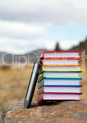Stack of printed books with electronic book reader