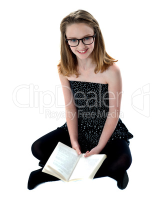 School girl sitting on floor holding book