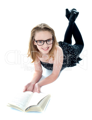 Smiling little girl lying with an open book