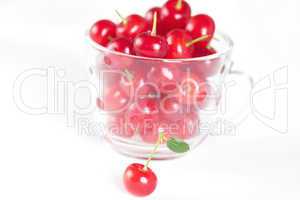 cherry with green leaf and a cup of cherries on a white backgrou