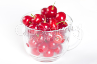 cherry with green leaf and a cup of cherries on a white background