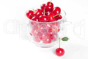 cherry with green leaf and a cup of cherries on a white background