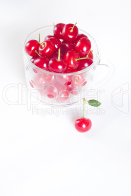 cherry with green leaf and a cup of cherries on a white background