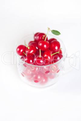 cherry with green leaf and a cup of cherries on a white backgrou