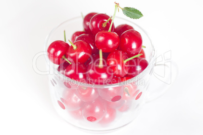 cherry with green leaf and a cup of cherries on a white backgrou