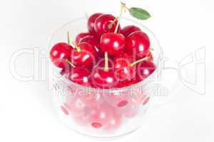 cherry with green leaf and a cup of cherries on a white backgrou