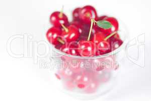 cherry with green leaf and a cup of cherries on a white backgrou