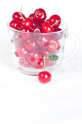 cherry with green leaf and a cup of cherries on a white backgrou