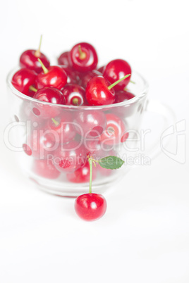 cherry with green leaf and a cup of cherries on a white backgrou