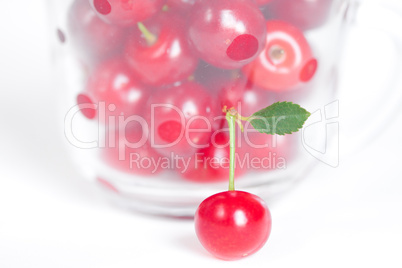 cherry with green leaf and a cup of cherries on a white backgrou