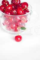 cherry with green leaf and a cup of cherries on a white backgrou