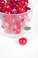 cherry with green leaf and a cup of cherries on a white backgrou